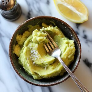 Mashed ripe avocado in a bowl with a fork ready to spread on toast.