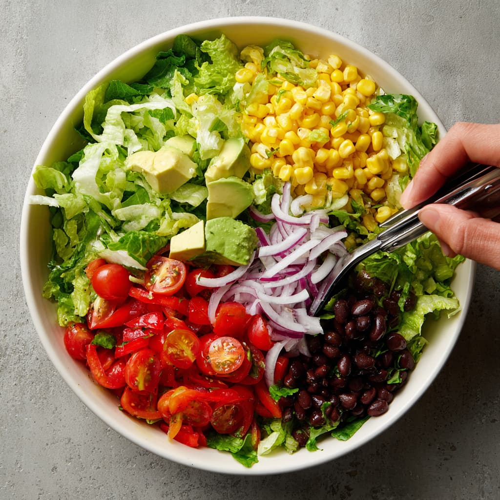 Adding fresh vegetables and beans to the Southwest chicken salad base.