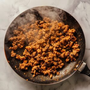 Ground turkey and black beans cooking in a skillet with taco seasoning.