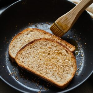 Whole grain bread slices toasting in a skillet with olive oil.