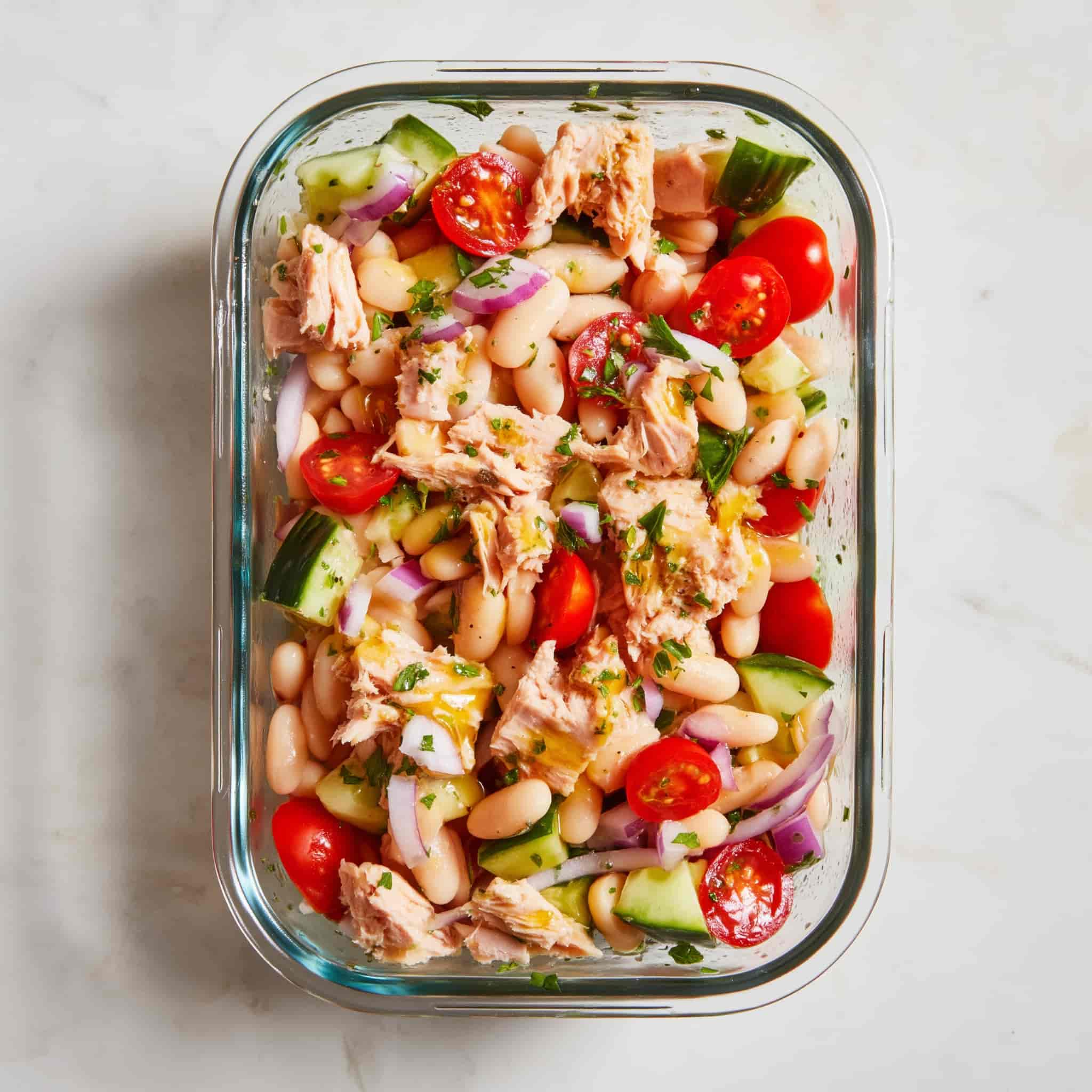 High protein tuna and white bean salad fully mixed with flaked tuna, cannellini beans, cherry tomatoes, cucumber, red onion, parsley, and lemon dressing evenly distributed