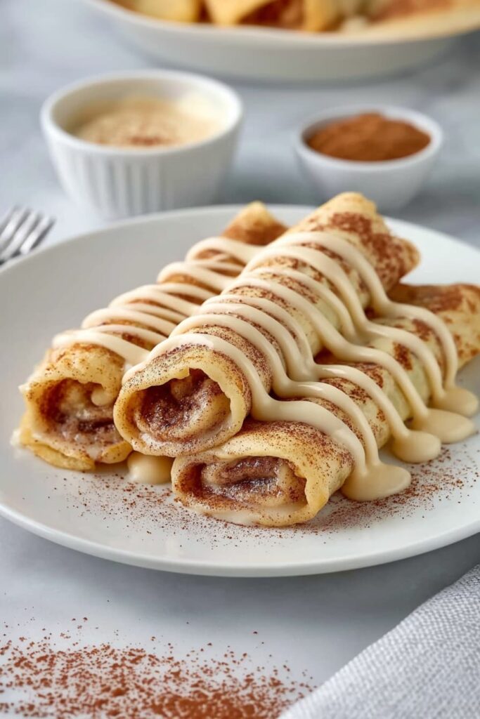 Rolled cinnamon roll high protein crepes with glaze and berries