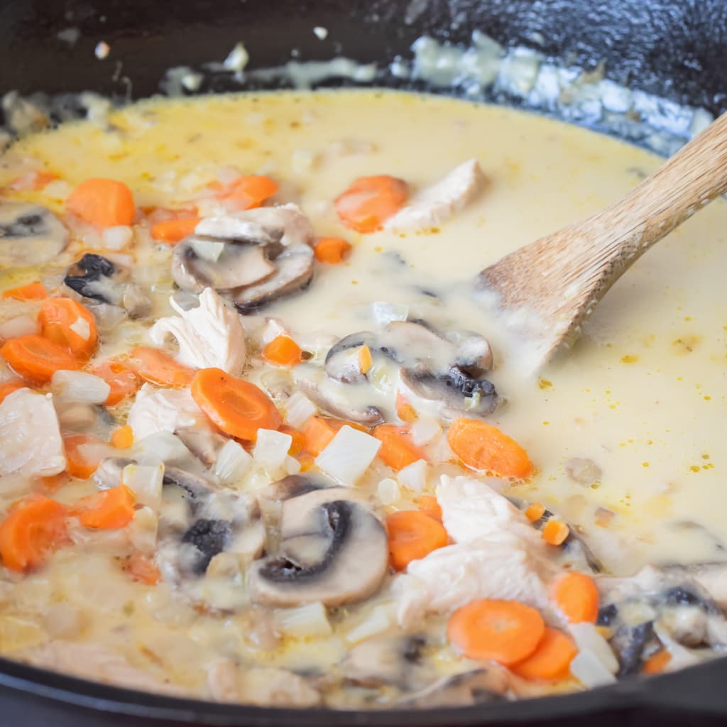 Creamy chicken pot pie style sauce thickening in a skillet