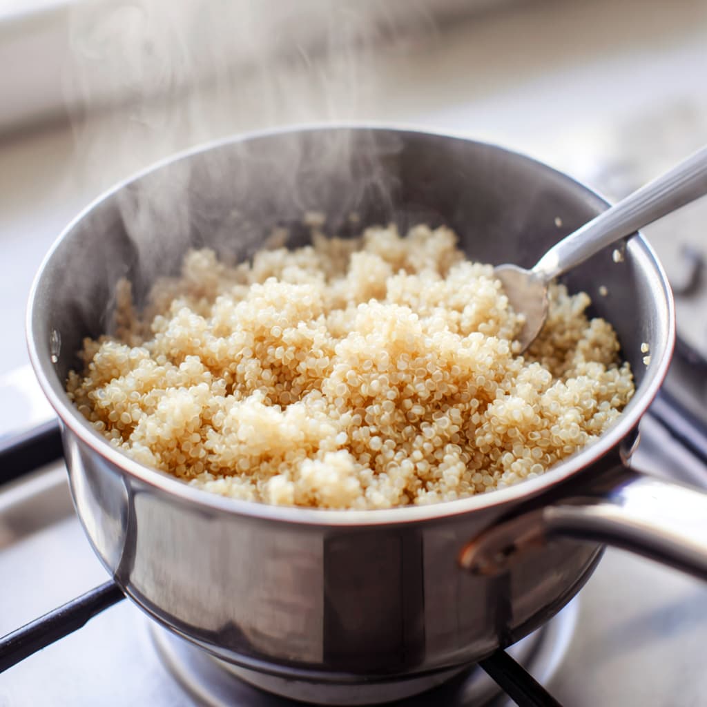 Fluffy cooked quinoa in a saucepan after simmering and fluffing with a fork