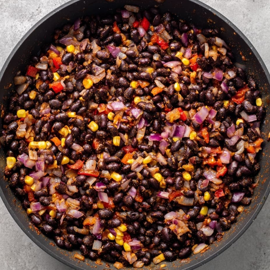 Black beans mixed with spiced onions, bell peppers, and corn in a skillet
