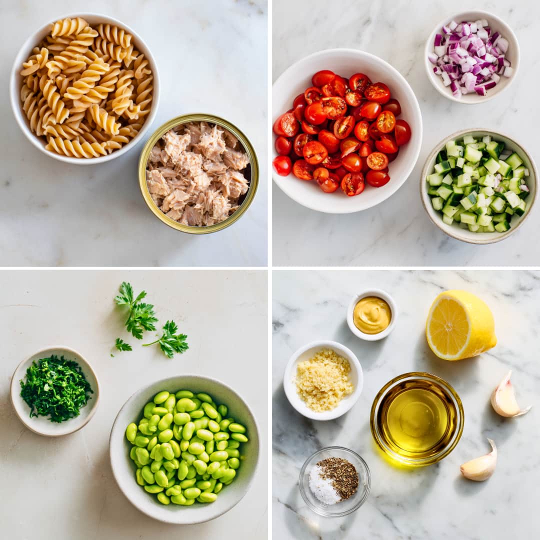 Ingredients for tuna edamame pasta salad laid out on a marble surface, including whole wheat rotini pasta, tuna, halved cherry tomatoes, diced cucumber, chopped red onion, shelled edamame, parsley, olive oil, lemon, Dijon mustard, garlic, salt, and pepper.