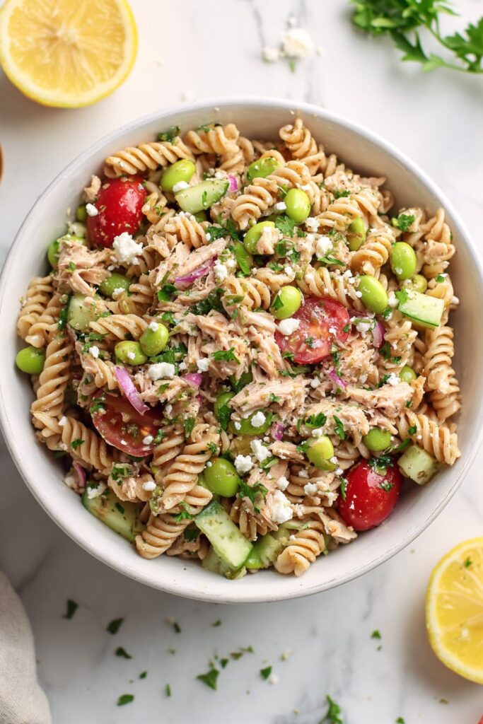 High protein tuna and edamame pasta salad made with whole wheat pasta, fresh vegetables, and lemon dressing in a white bowl.