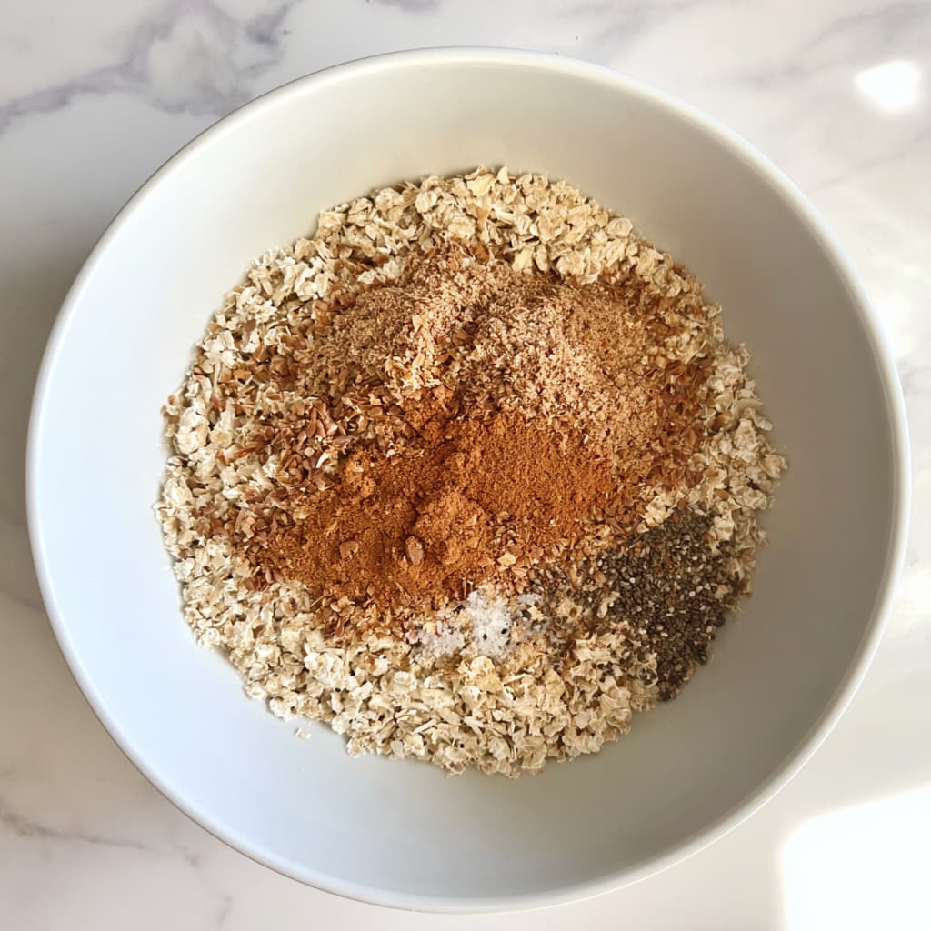 Dry ingredients including oats, flaxseed, cinnamon, chia seeds, and salt in a mixing bowl before combining