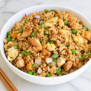 healthy Chinese chicken fried rice topped with sliced green onions in a skillet.