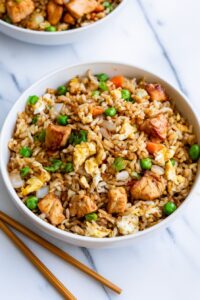 healthy Chinese chicken fried rice topped with sliced green onions in a skillet.