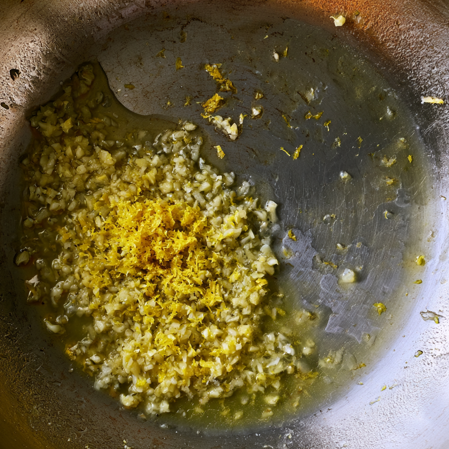 Garlic in a pan mixed with lemon juice and zest forming a light glossy base